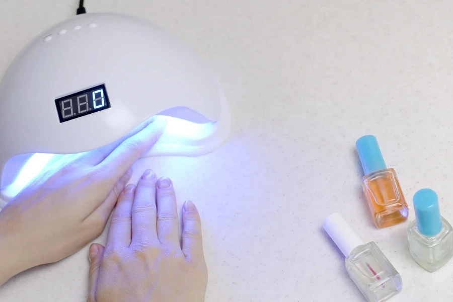 Woman's coated nails inside nail lamp