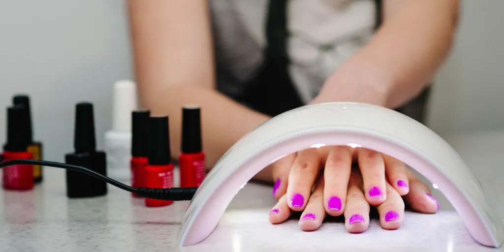 Woman's freshly manicured nails under nail lamp