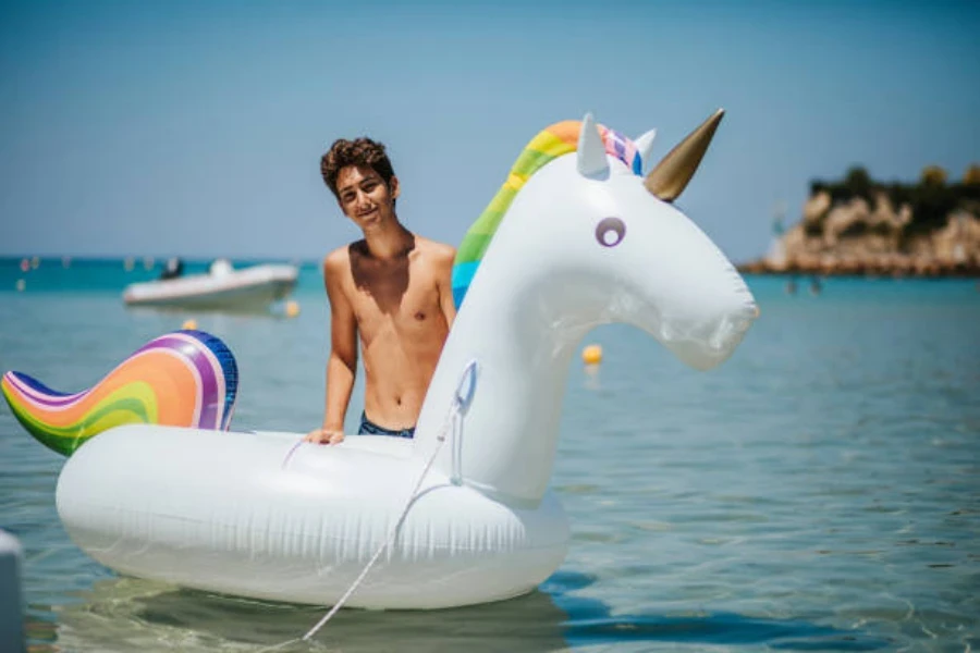 Young man standing in water next to unicorn swimming ring