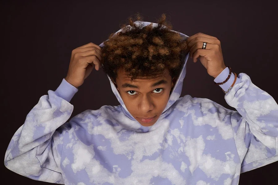 a black teen wearing a white-purple pattern hoodie