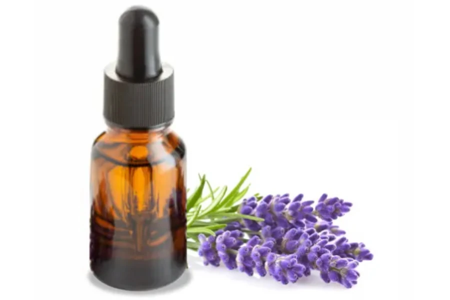 A bottle of lavender essential oil and flower behind it
