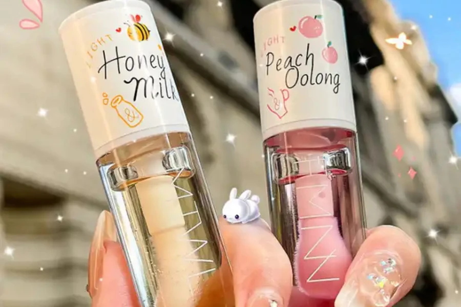A hand holding two lip oils in different shades