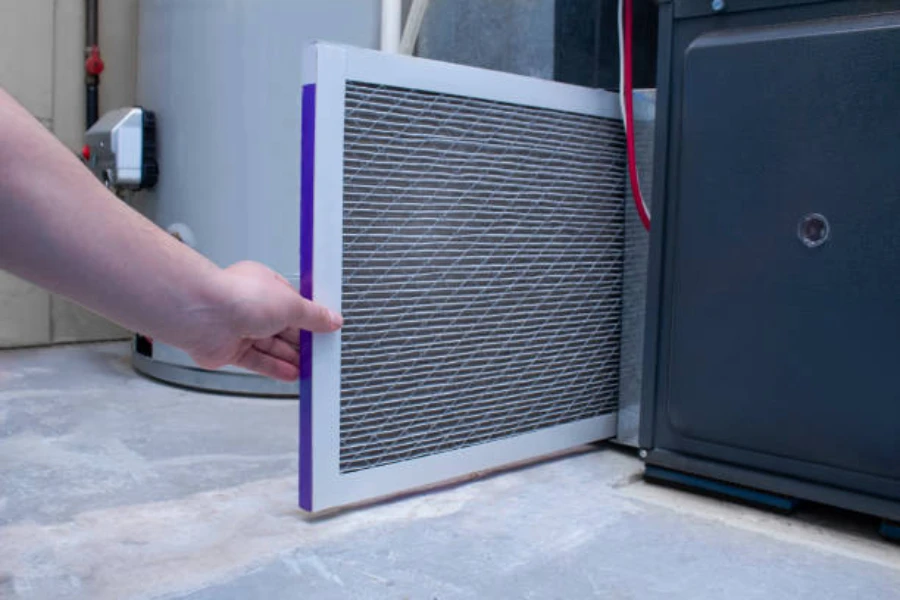 Um homem trocando um filtro de ar em uma fornalha