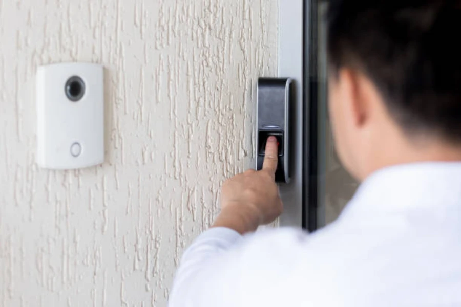 A man using a smart lock next to a smart doorbell