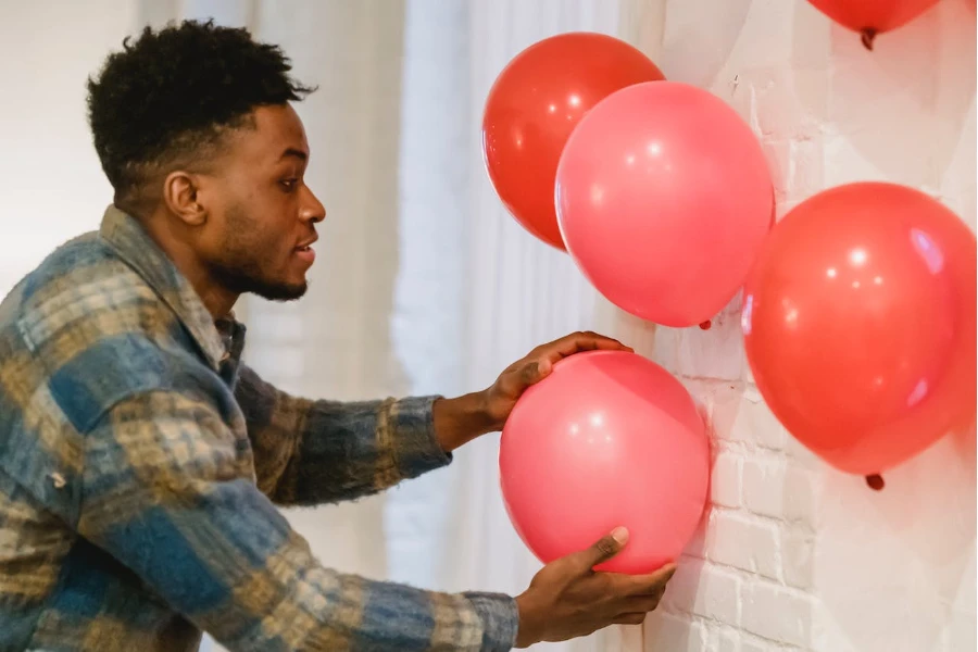 A man using double-sided tape to stick balloons to a wall