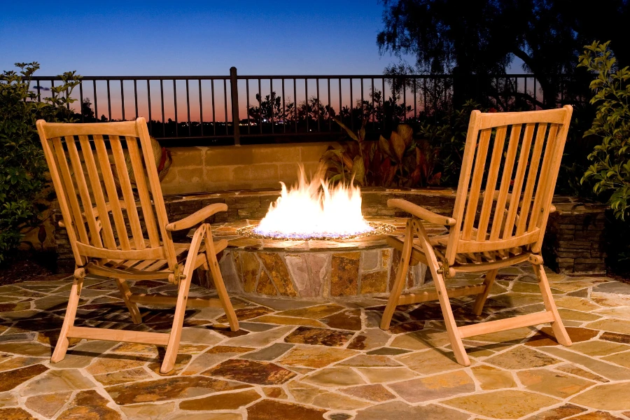 A propane fire-pit in the backyard with two empty chairs