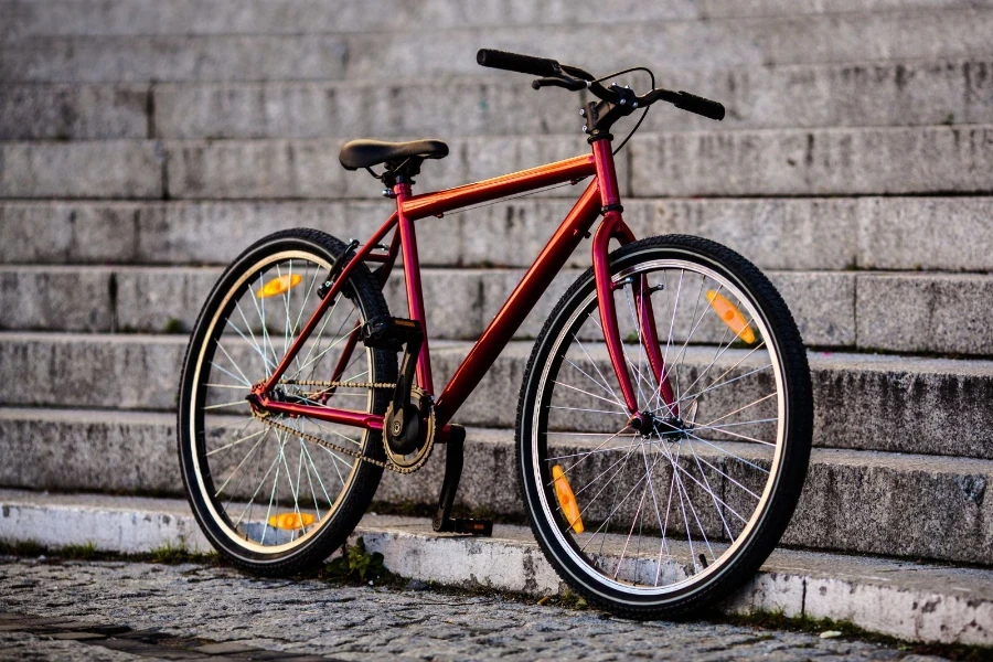 a red hybrid bike parked at the foot of the steps