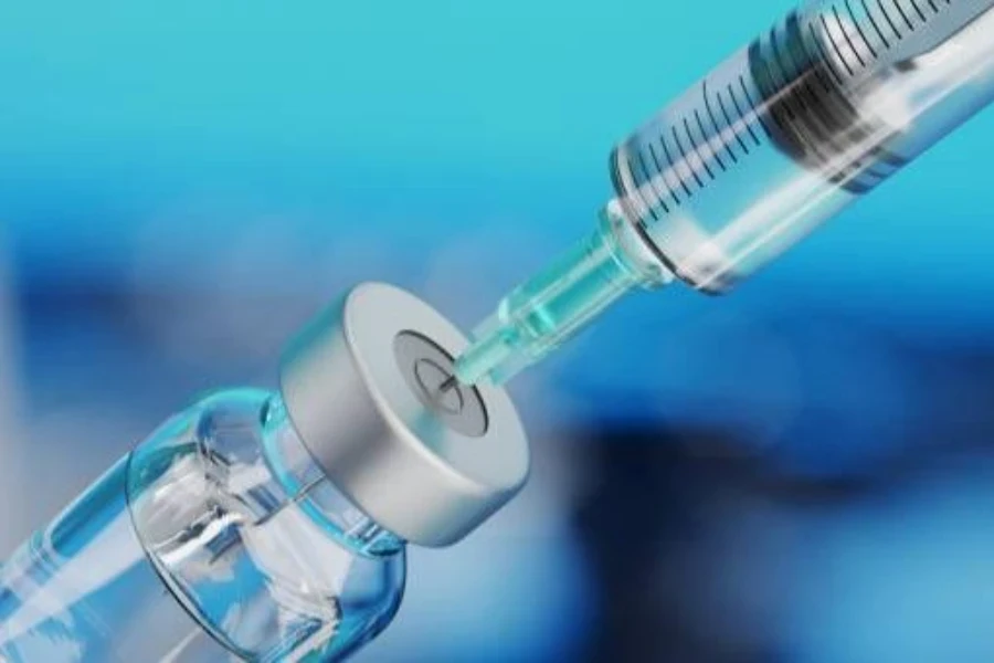 a syringe drawing transparent liquid from a small container