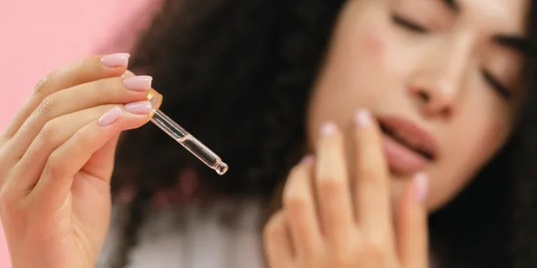 A woman holding essential oil in a dropper