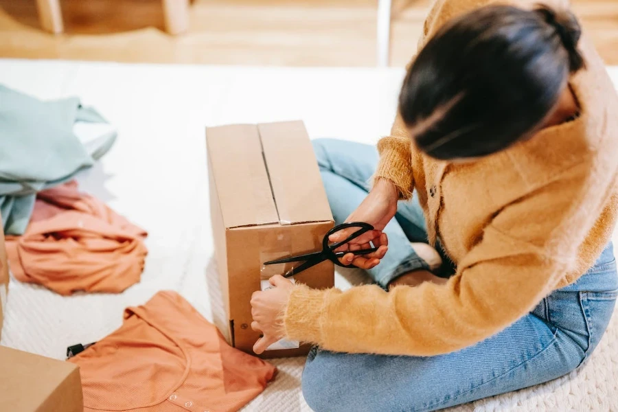 Eine Frau klebt ein Paket mit Klebeband an einem Paket fest