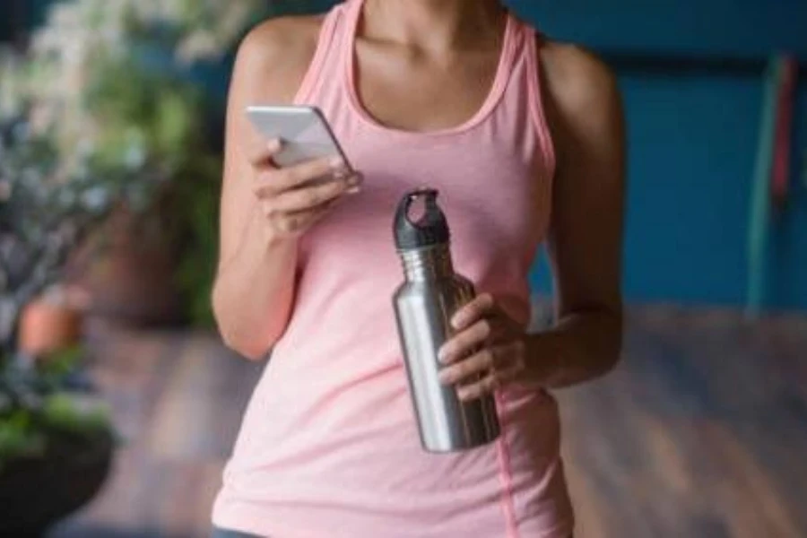 seorang wanita muda memegang botol air olahraga terisolasi