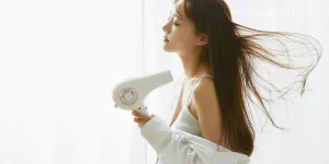 a young woman holding a hair dryer