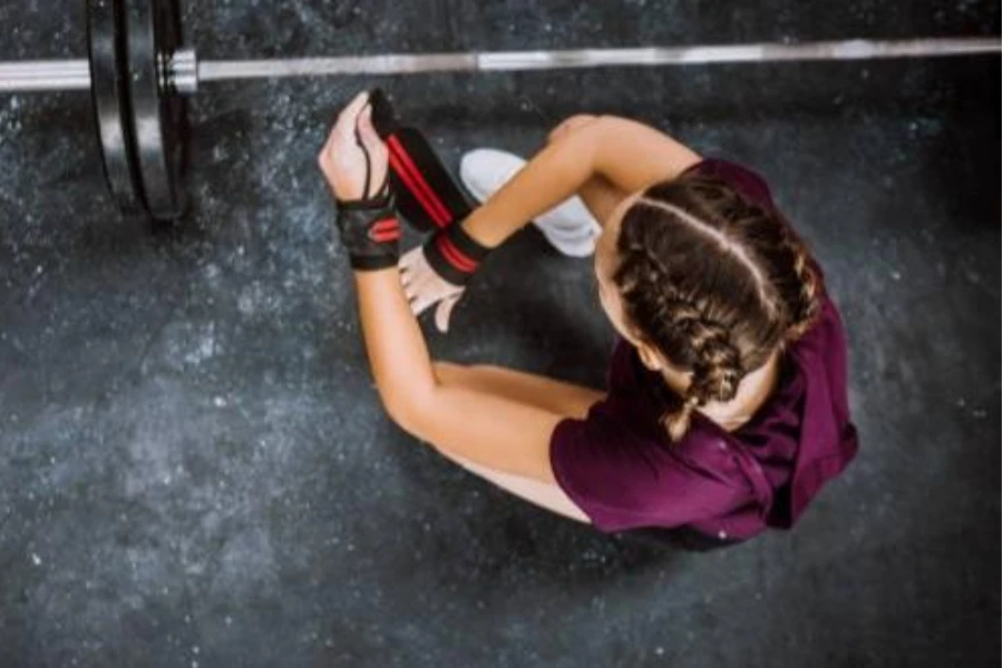 a young woman putting on a red weightlifting wrist wrap