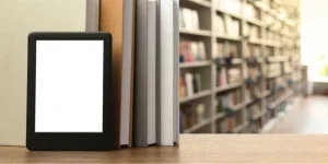 An e-reader placed in front of a stack of books