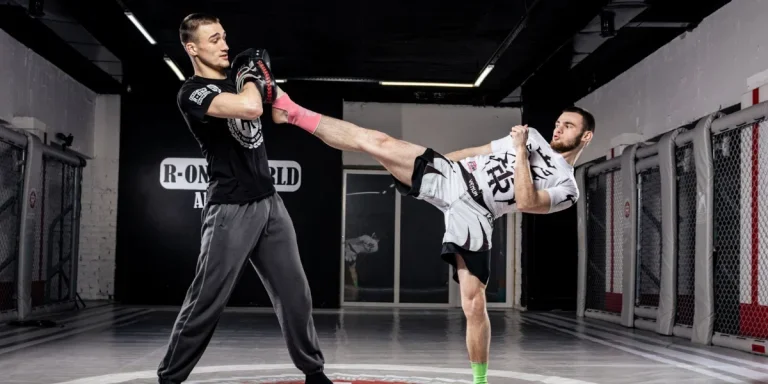 An MMA practitioner strikes a high pad with a kick