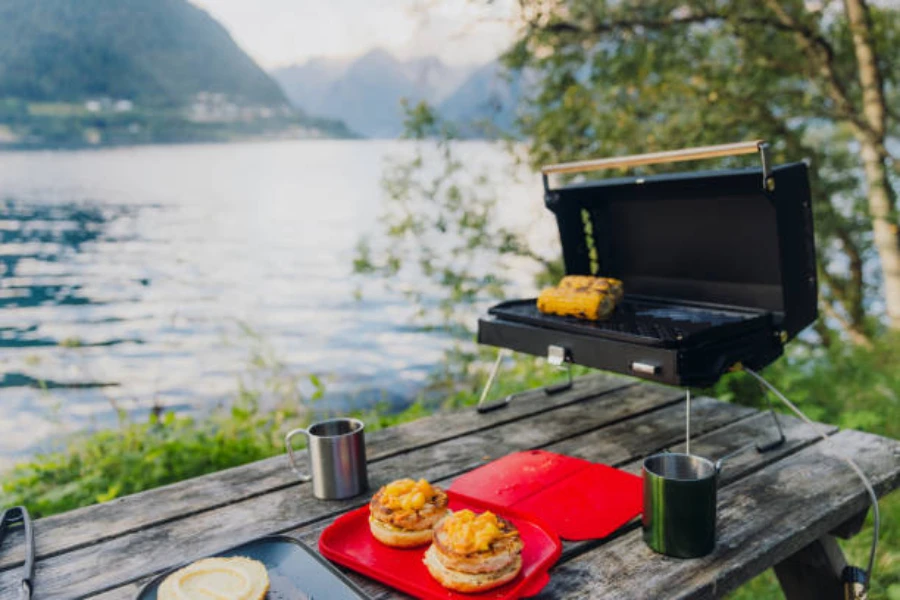black electric grill set up next to a lake