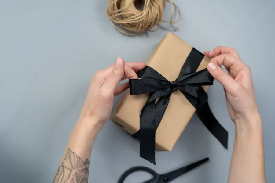 Caja de regalo marrón con cinta negra.