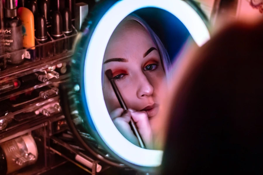 Close up of person applying makeup in a light up mirror