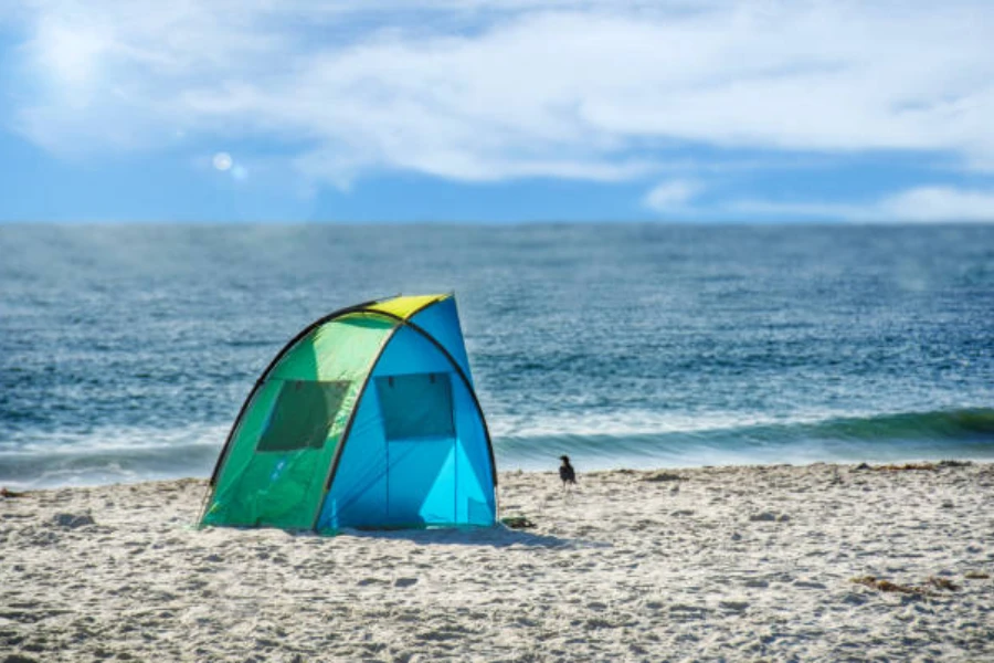 colorful privacy tent set up next to water on beach