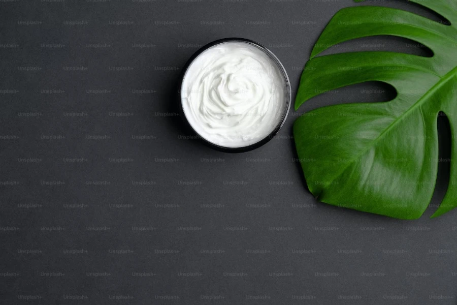 cream in a jar next to a leaf