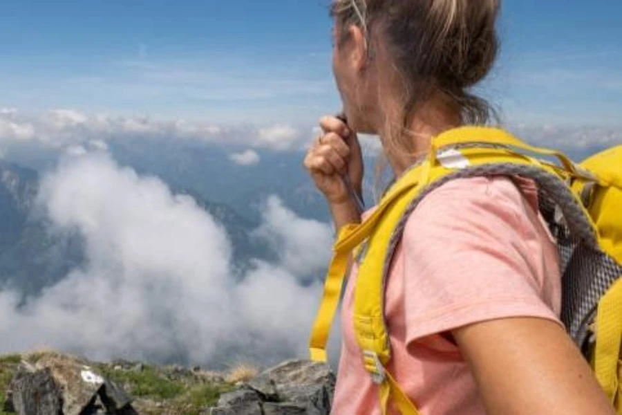 female hiker drinking from a yellow hydration pack