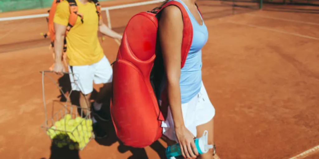 female tennis player walking with red tennis racket bag