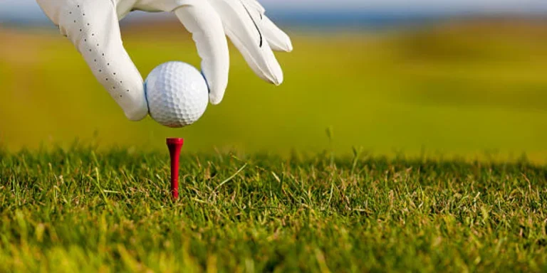 Golfer placing ball on top of red golf tee
