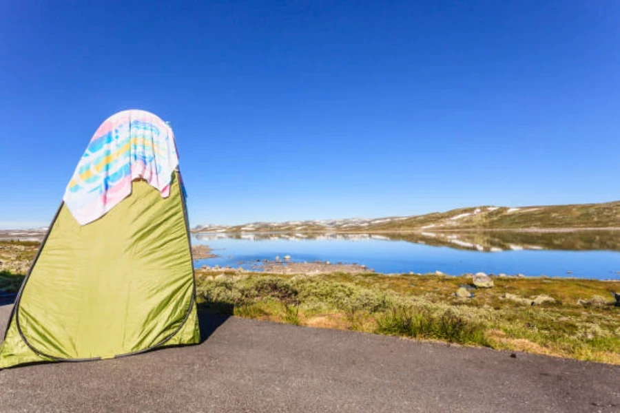 barraca de chuveiro pop-up verde com vista para um lago