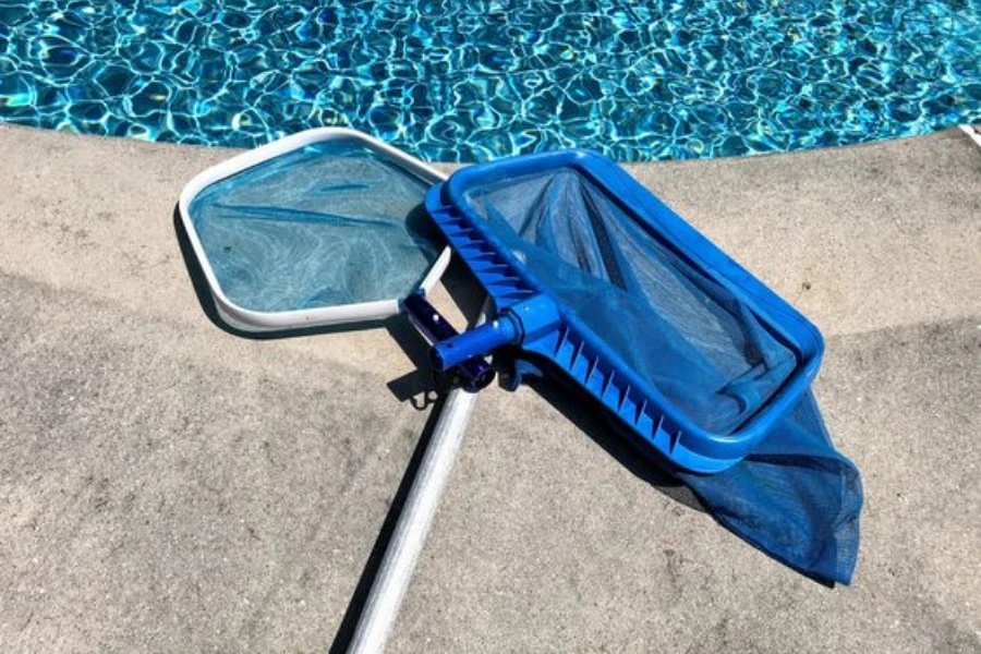 Hand-held pool skimmer net on the floor near a pool