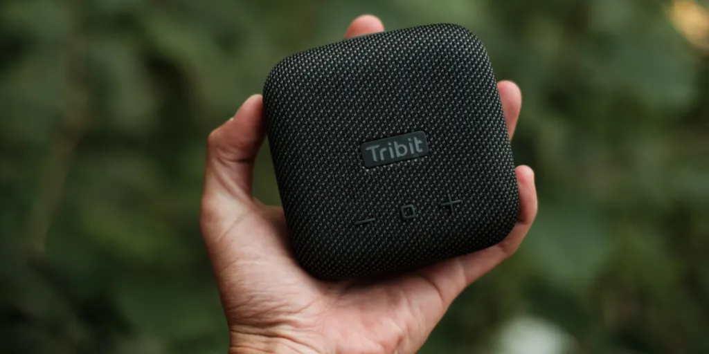 Hand holding a square, branded wireless speaker