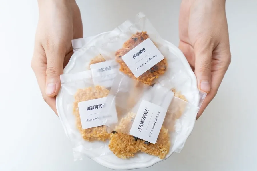 Plastik ambalajlara paketlenmiş kurabiyeleri tutan eller
