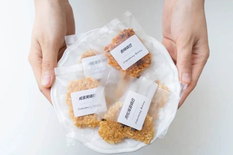 Hands holding cookies packaged in plastic wrappers