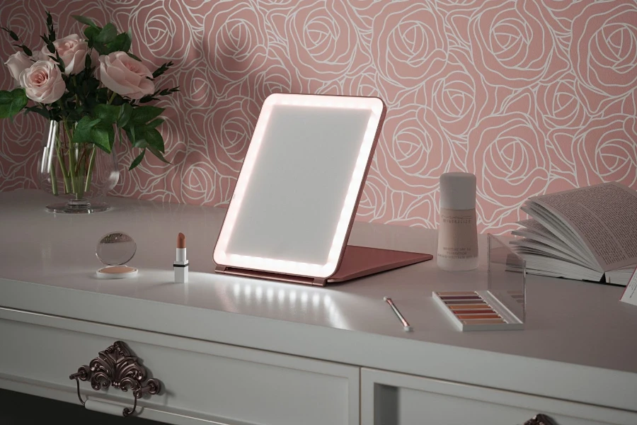 Light up makeup mirror sitting on a white dresser beside makeup