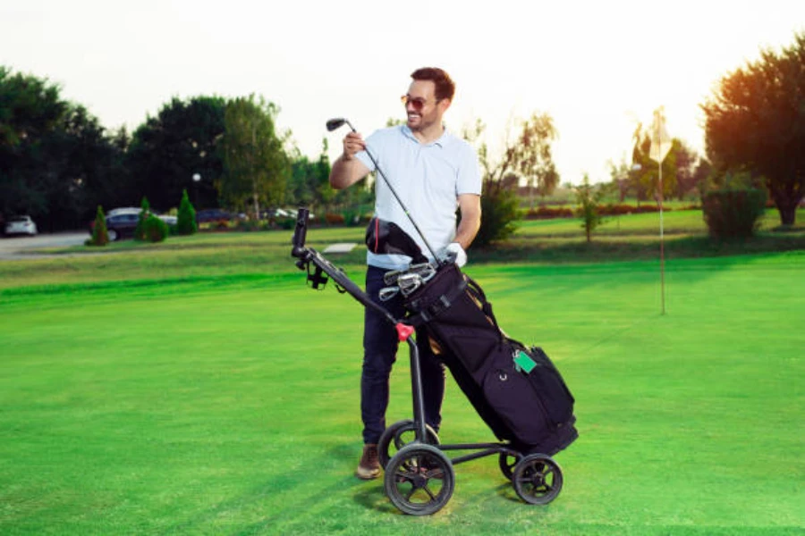 Man pulling club out of 3 wheel golf trolley