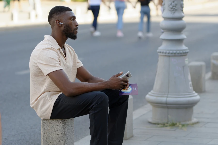man sitting on a stone bench wearing open earbuds