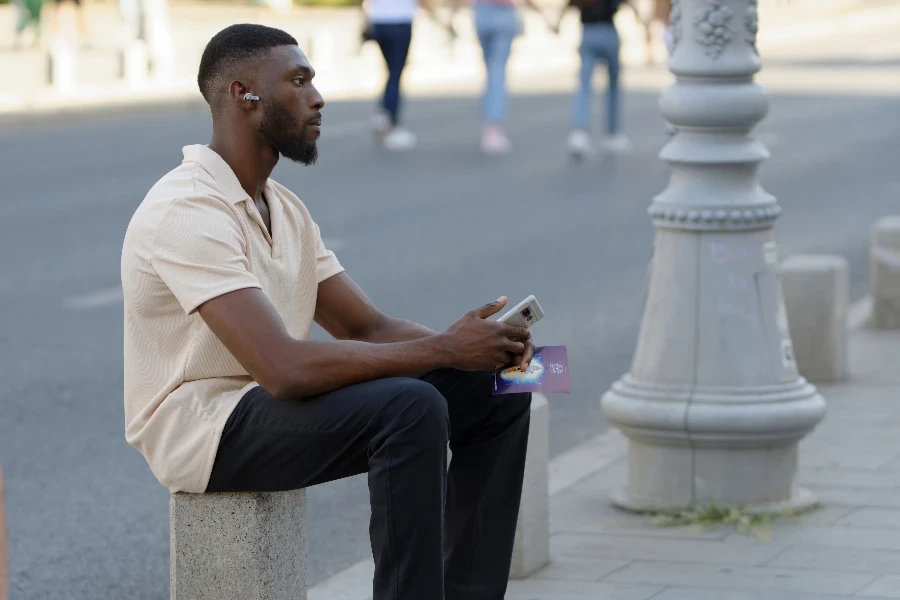 homme assis sur un banc de pierre portant des écouteurs ouverts