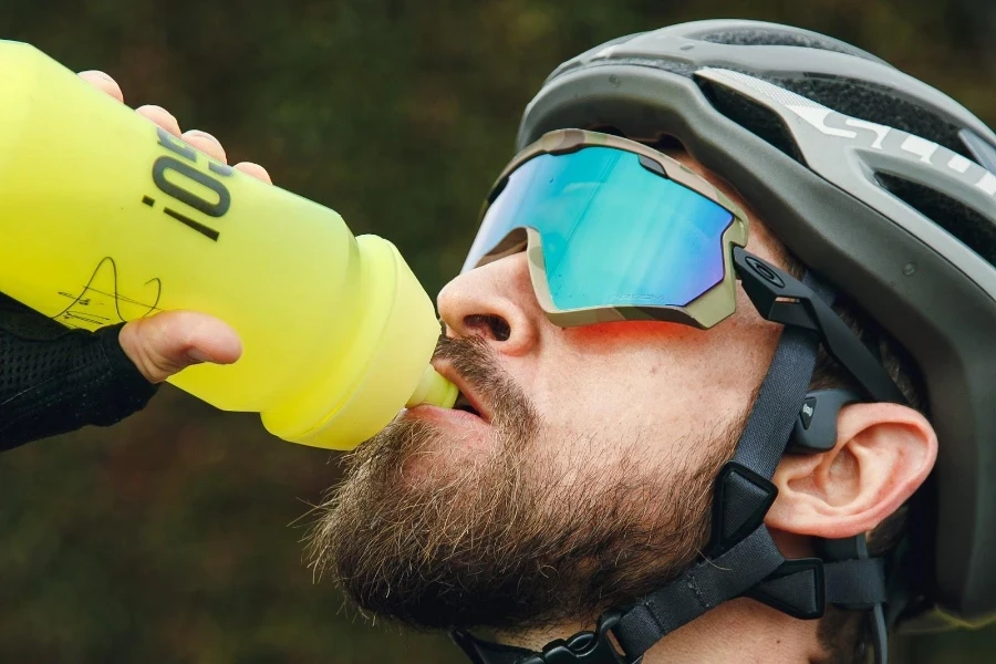 uomo di mezza età che beve da una bottiglia d'acqua spremuta