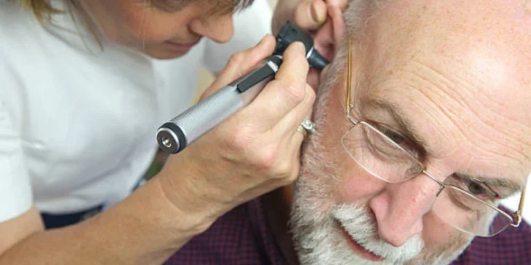 Nurse conducting ear wax removal on a senior citizen
