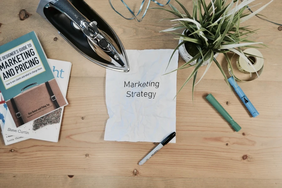 Paper on a desk that says ‘marketing strategy’ with other desk supplies
