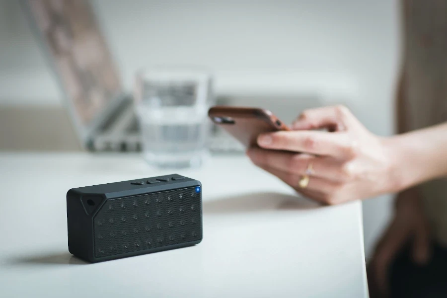 Person connecting to a black Bluetooth wireless speaker