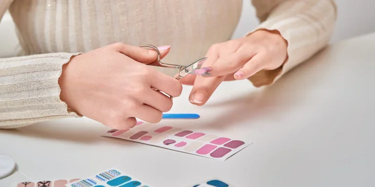 Person cutting and shaping nails after applying a nail sticker