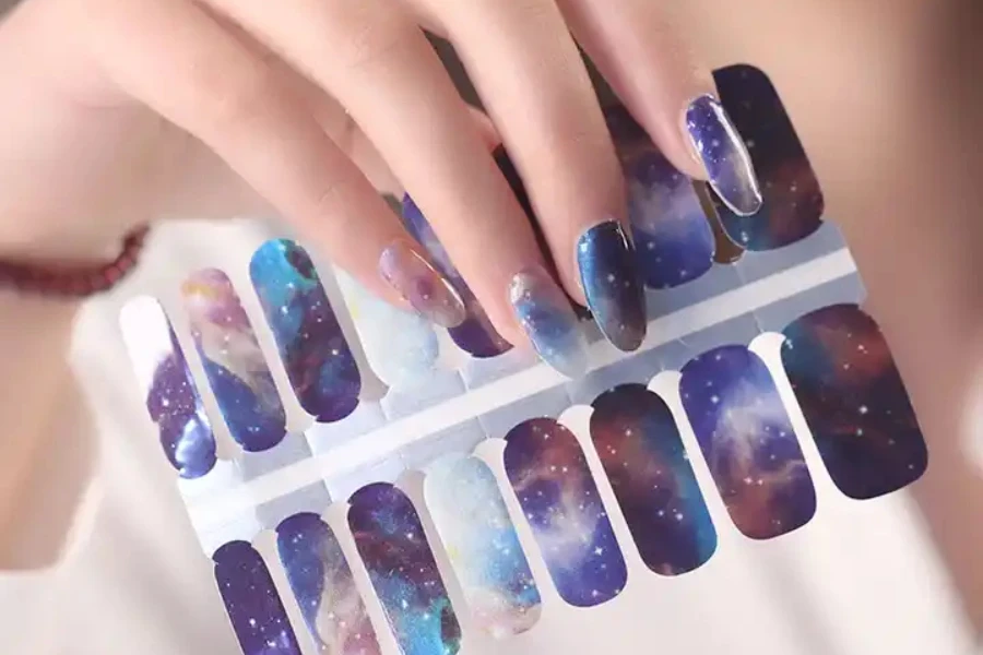 Person mit Galaxie-Nagelaufklebern