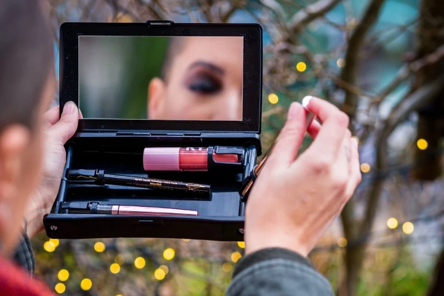 Persona mirando en un espejo de maquillaje portátil