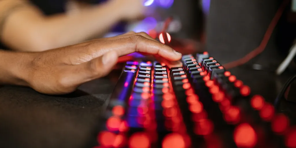 person pressing down a key on a mechanical keyboard lit up red