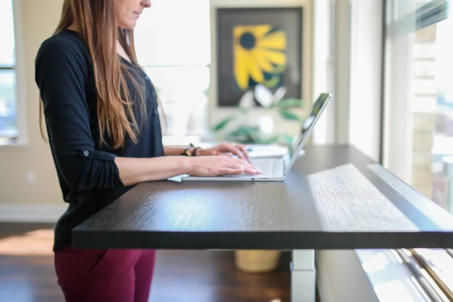 Person typing on a laptop at a standing desk