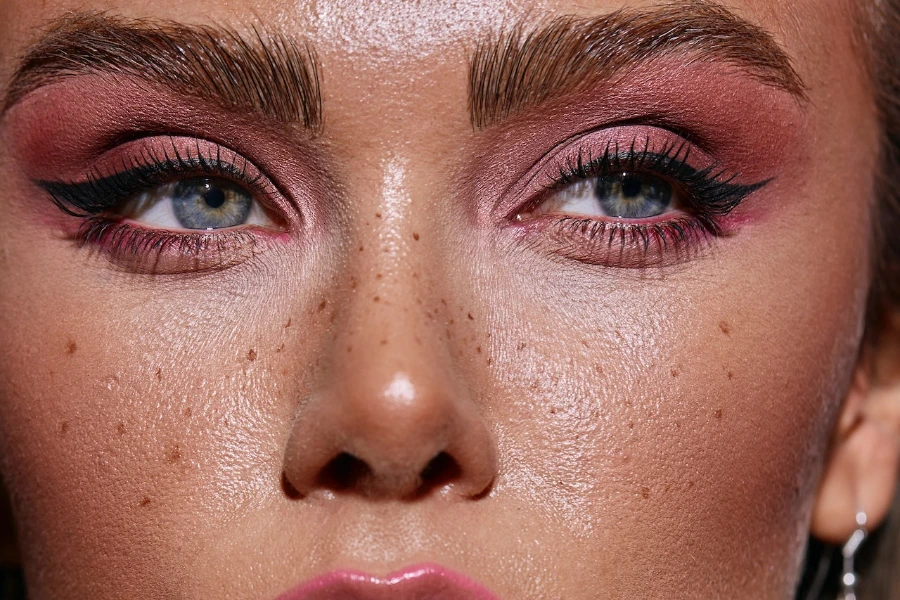 Person mit aktuellen Make-up-Trends wie künstlichen Sommersprossen und geformten Augenbrauen