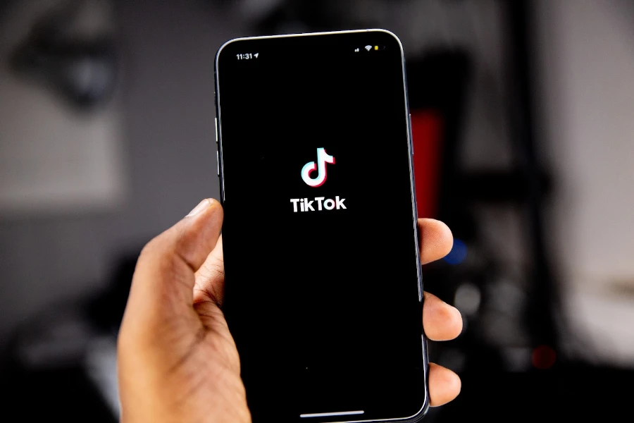 Persons holding up a smartphone with the TikTok logo filling the screen
