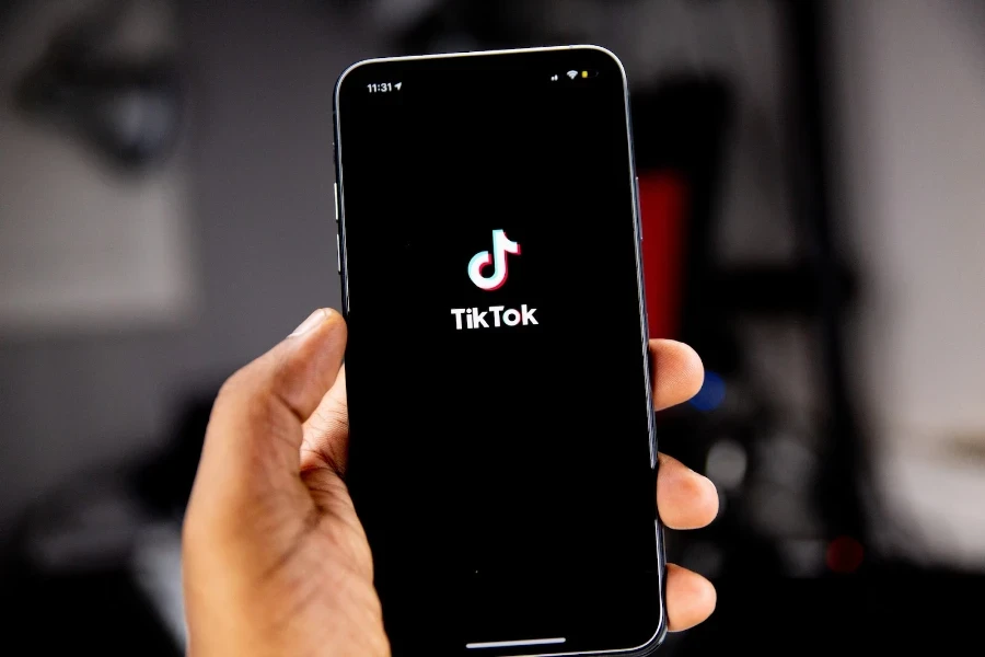 أشخاص يحملون هاتفًا ذكيًا يحمل شعار TikTok الذي يملأ الشاشة