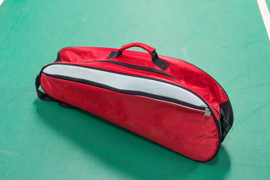 red and white 3 racket tennis bag sitting on court