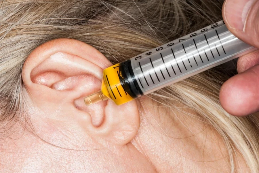 Red-haired female with an ear syringe inserted into her ear